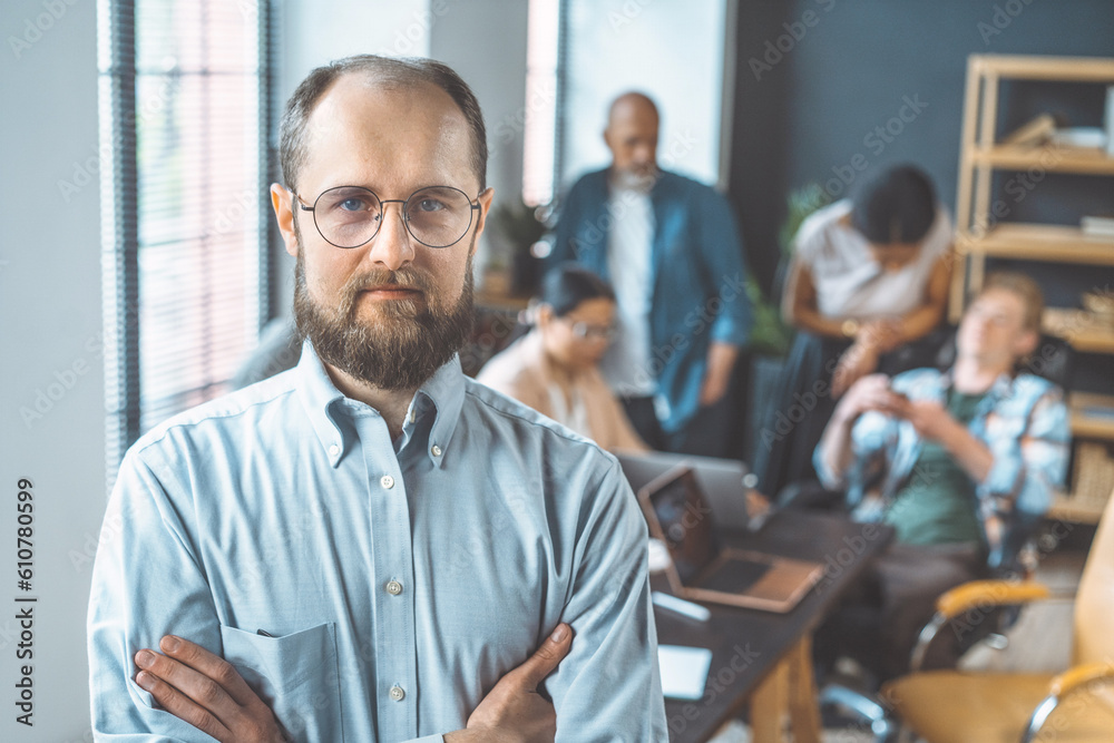 Team leader depicted through portrait of confident businessman, set against background of team working in office. Leader exemplifies qualities of leadership, professionalism, and business acumen. High Team leader depicted through portrait of confident businessman, set against background of team working in office. Leader exemplifies qualities of leadership, professionalism, and business acumen. High