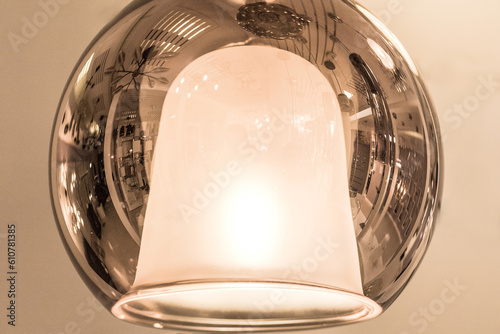 Round glass LED ceiling-mounted chandelier with a decorative element in the shape of a bell inside in the interior close-up