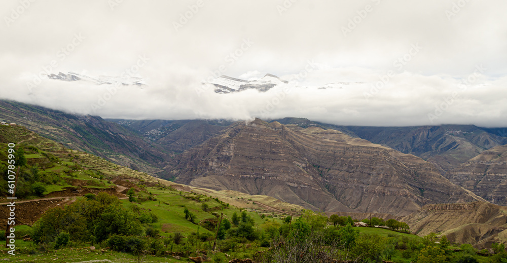 Fototapeta premium Panoramic view of the cloud-covered mountains in a green valley