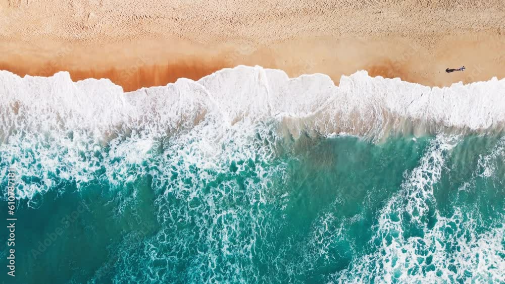 Aerial top down view of the sandy beach and crushing waves