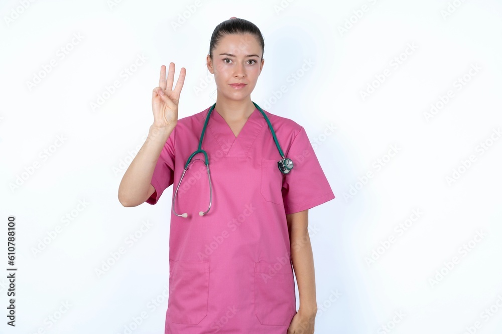 young caucasian doctor woman wearing pink uniform over white background showing and pointing up with fingers number three while smiling confident and happy. young caucasian doctor woman wearing pink uniform over white background showing and pointing up with fingers number three while smiling confident and happy.