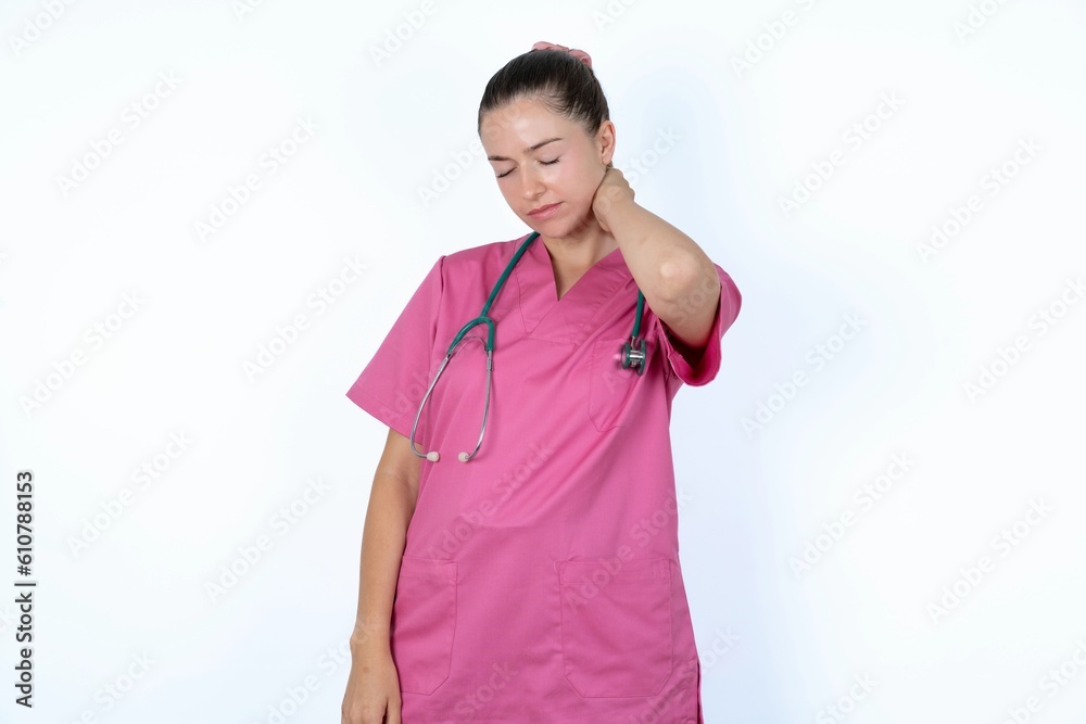 young caucasian doctor woman wearing pink uniform over white background suffering from back and neck ache injury, touching neck with hand, muscular pain.