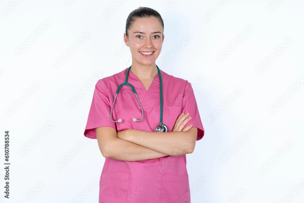 young caucasian doctor woman wearing pink uniform over white background frowning his face in displeasure, keeping arms folded, waiting for an explanation. young caucasian doctor woman wearing pink uniform over white background frowning his face in displeasure, keeping arms folded, waiting for an explanation.