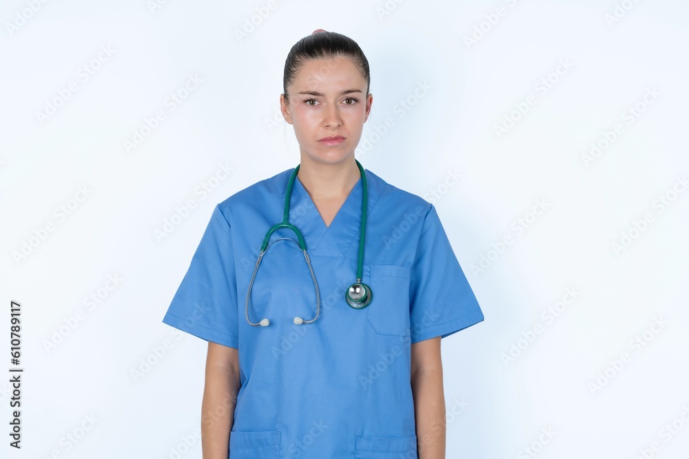 Offended dissatisfied young caucasian doctor woman wearing medical uniform over white background with moody displeased expression at camera being disappointed by something Offended dissatisfied young caucasian doctor woman wearing medical uniform over white background with moody displeased expression at camera being disappointed by something