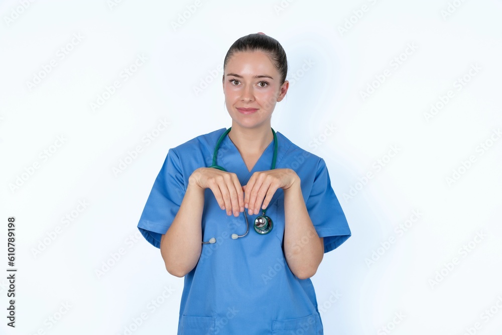 young caucasian doctor woman wearing medical uniform over white background makes bunny paws and looks with innocent expression plays with her little kid young caucasian doctor woman wearing medical uniform over white background makes bunny paws and looks with innocent expression plays with her little kid