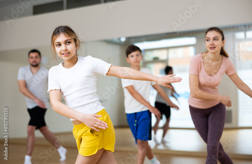 Portrait of cheerful teen girl practicing vigorous movements in dance class with brother and parents. Family active lifestyle concept