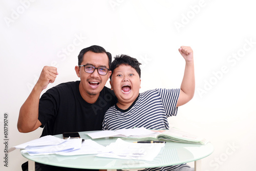 Excited Asian school boy studying with his dad at home photo