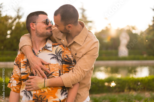 Homosexual couple embraced giving each other a kiss at sunset in a park in the city. Diversity and lgbt concept © unai
