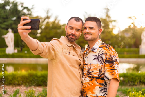 Homosexual couple taking a selfie at sunset in a park in the city. Diversity and lgbt concept © unai