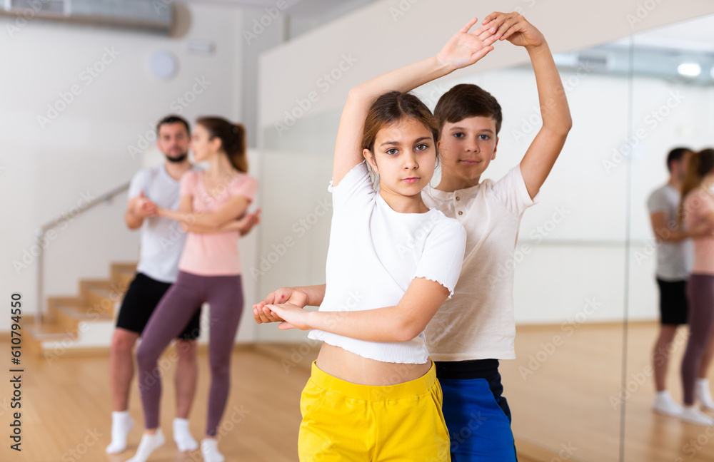 Portrait of smiling girl with boy performing pair dance movements, family practicing dance in pair