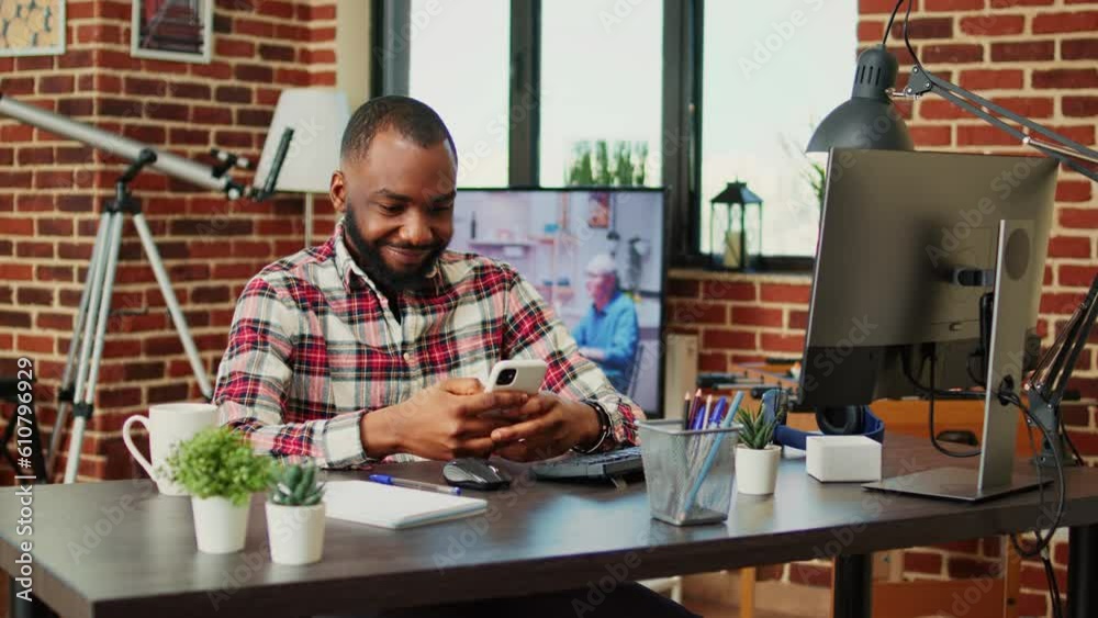 Relaxed african american man scrolling on his phone entertained by social media activity. Happy cheerful person enjoying himself, chatting with online friends over the phone in cozy stylish home Relaxed african american man scrolling on his phone entertained by social media activity. Happy cheerful person enjoying himself, chatting with online friends over the phone in cozy stylish home