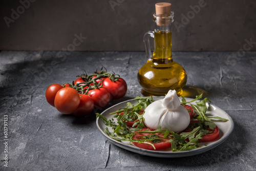 Burrata cheese with tomatoes, arugula and pesto sauce on a marble table.