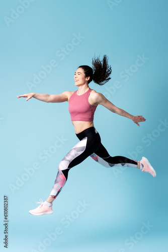 Cheerful female jogger, active competitive determined sportswoman jumping high