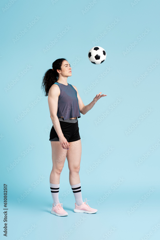 Successful female athletic woman, soccer player, standing alone playing with soccer ball