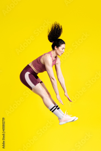 Vertical studio portrait of a successful strong sportswoman jumping high up