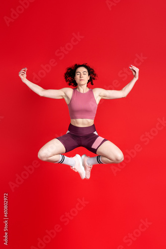 Female athlete in activewear, determined sportswoman, closed eyes, meditating and jumping