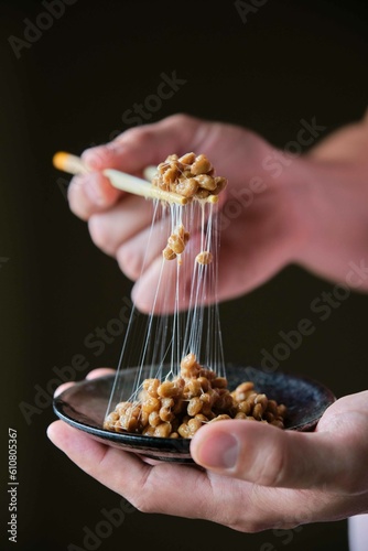 Hand holding chopsticks with natto fermented soy beans.
