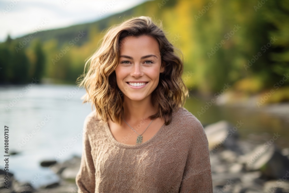 Portrait of a beautiful young woman smiling at the camera while standing by the river