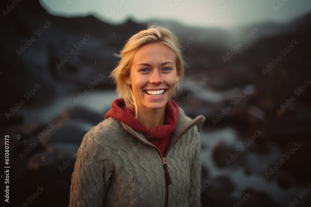 Portrait of a smiling young woman standing in the middle of a rocky beach Portrait of a smiling young woman standing in the middle of a rocky beach