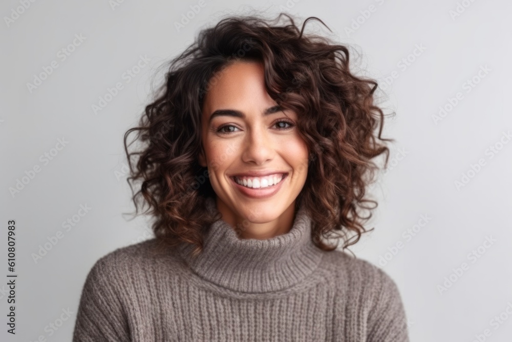 Portrait of a beautiful young woman smiling and looking at camera over gray background