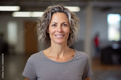 Portrait of smiling mature woman standing in fitness studio with arms crossed