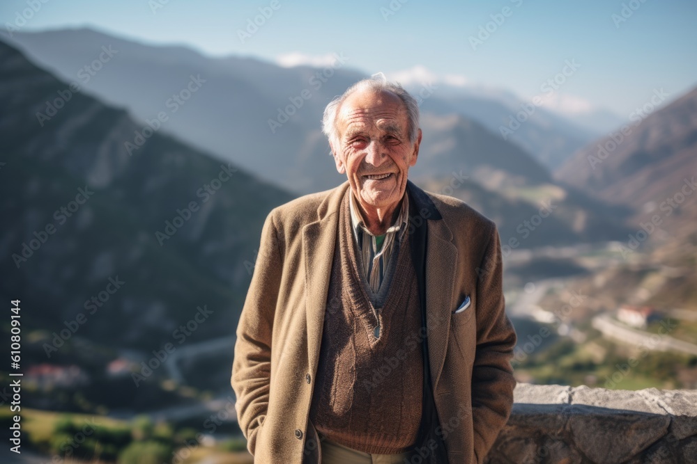 Portrait of a happy senior man standing on top of a mountain