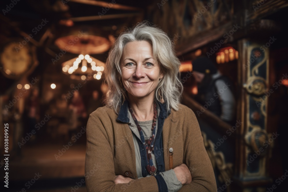 Portrait of smiling senior woman standing with arms crossed in cafe.