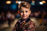 Portrait of a cute little boy with blond hair, dressed in a jacket and bow tie.