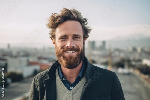 Portrait of handsome man with beard, looking at camera and smiling while standing outdoors