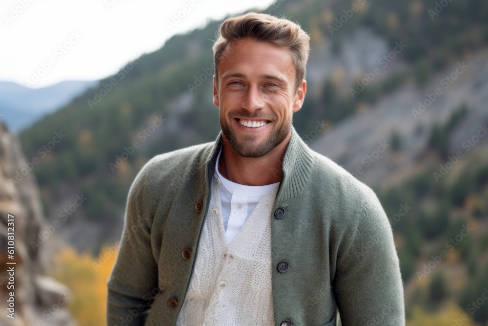 Portrait of a handsome young man smiling at the camera while standing in the mountains