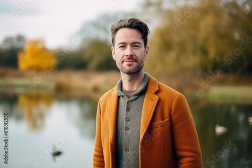 Medium shot portrait photography of a pleased man in his 30s that is wearing a chic cardigan against a tranquil park with a pond and ducks background .  Generative AI