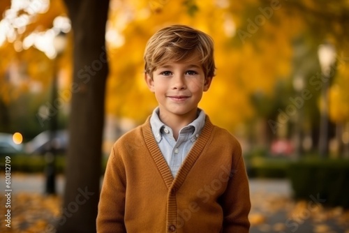 Portrait of a cute little boy standing in the autumn park.
