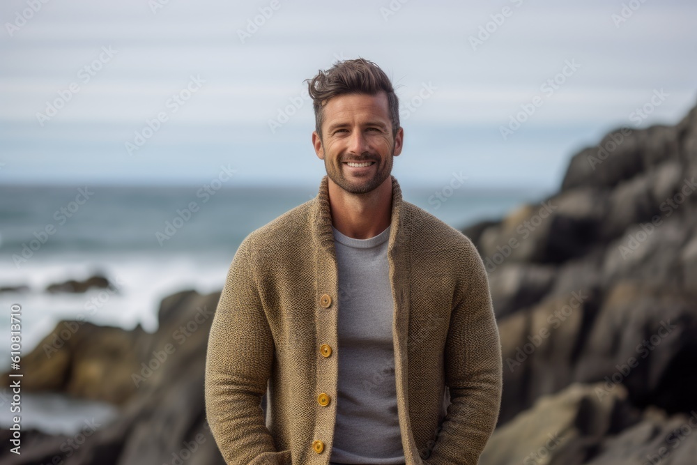 Portrait of handsome young man smiling at camera on the beach at autumn day