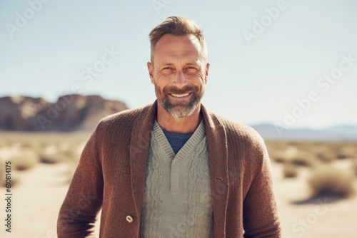 Medium shot portrait photography of a satisfied man in his 40s that is wearing a chic cardigan against a desert background . Generative AI