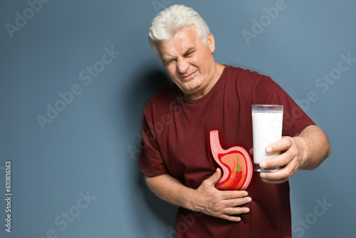 Billede på lærred Mature man with glass of milk suffering from heartburn on color background