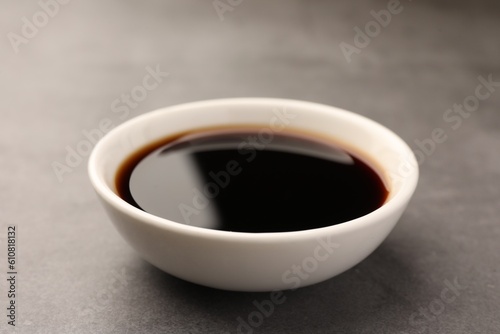 Bowl of soy sauce on grey table, closeup