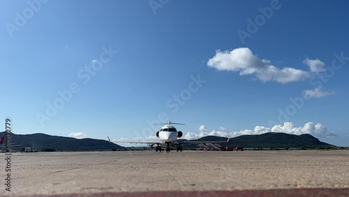 Front view of a white color medium size Bombardier CRK  jet parking in Ibiza’s airport, Spain, in a splendid spring day.