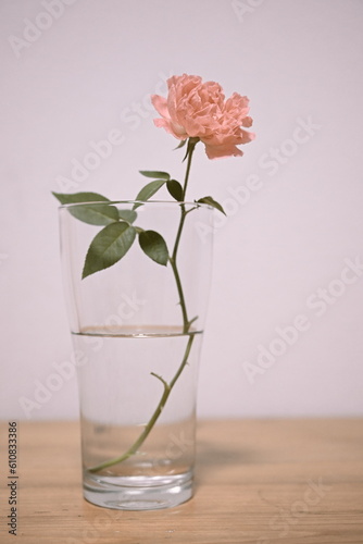 Pink roses in glass on wooden table