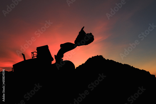 Wheel loader  silhouette are digging the soil in the construction site. on the red sky  background