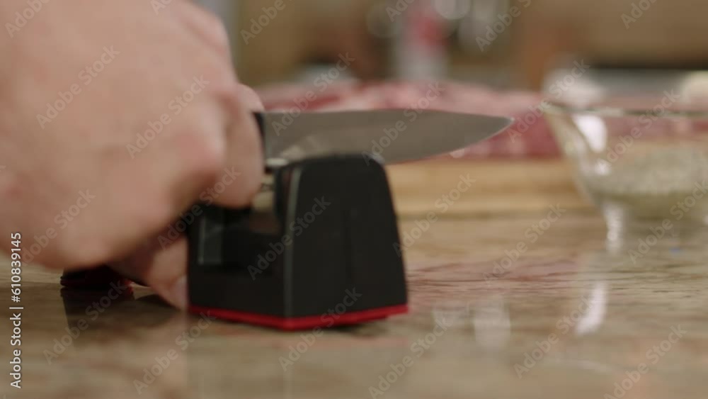 Rack focus from raw BBQ pork ribs to man sharpening knife in slow motion Rack focus from raw BBQ pork ribs to man sharpening knife in slow motion
