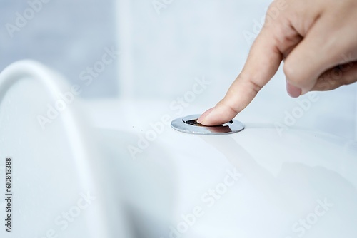 Woman's hand closeup flushing the toilet can be used for plumbing blockages and clogged drain concept photo