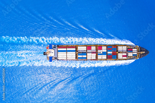 Aerial top view of cargo maritime ship with contrail in the ocean ship carrying container and running for export concept technology freight shipping.