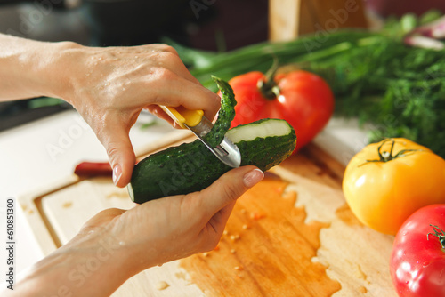 Female hand with peeler and cucumber photo