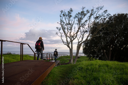 People walking on raised boardwalk around the crater at Mt Eden summit at sunrise. Auckland.