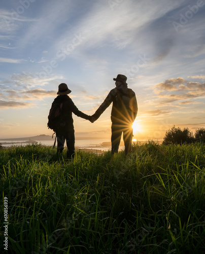 Obraz na płótnie Couple standing on Mt Eden summit and looking at Rangitoto Island at sunrise. Auckland. Vertical format. w salonie