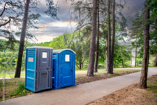 Two portable toilets in a park photo