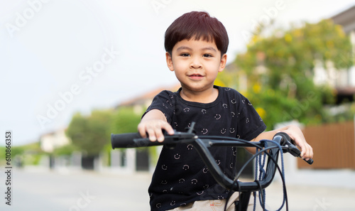 Funny Asian kid smilling and riding bike outdoor in autumn day.
