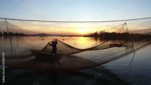 Fishermen throwing fishing net during dawn with boats at the sea gate. Concept Fisherman's life style. Cua Dai, Hoi An, Asia, Vietnam.