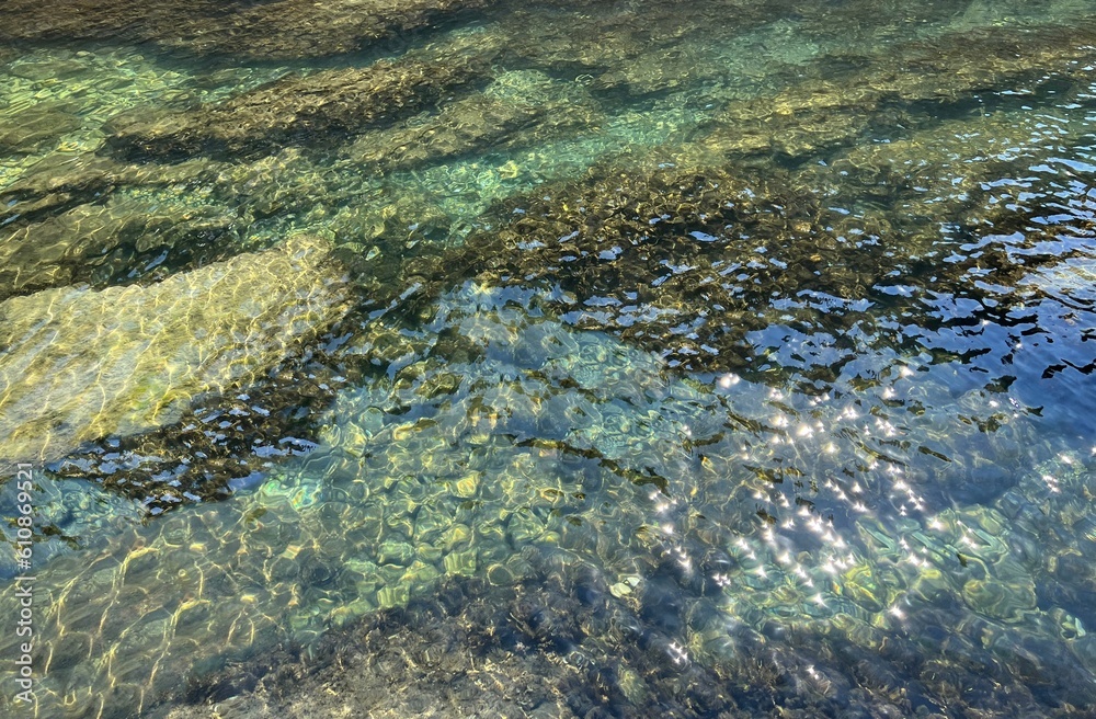 Sea water underwater stones pebbles in clear shiny waters.