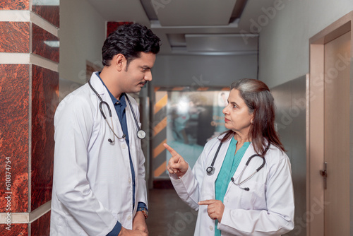 Senior female doctor discussing to assistance doctor at hospital.